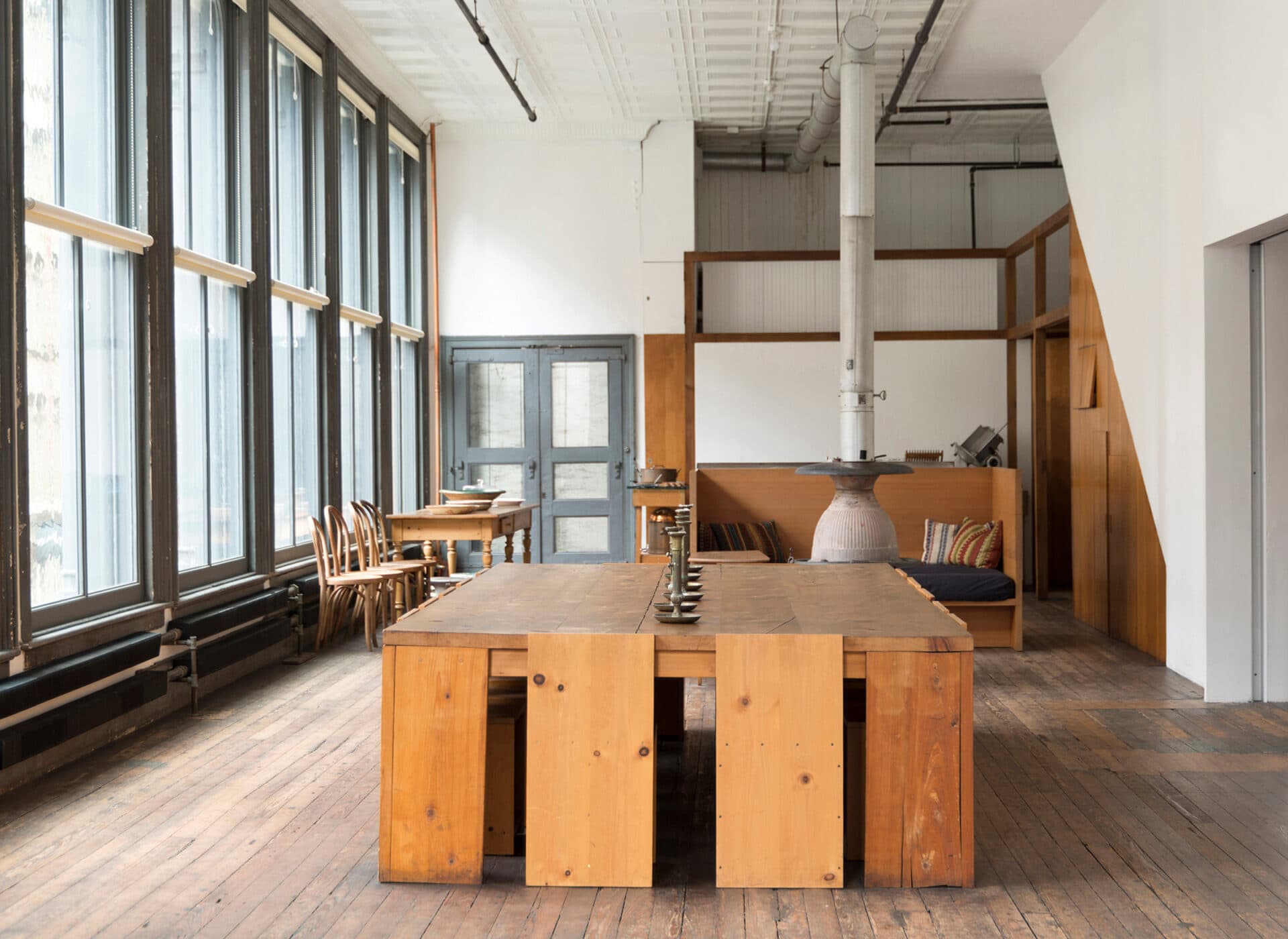 A floor of 101 Spring Street: cast-iron columns, wide board floor, a long plain table, and work installed permanently along the walls under daylight from two sides.